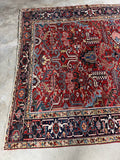 One end view of antique Persian rug highlighting the saturated color and bold design.