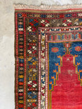 Corner view of hand knotted wool rug with eight pointed star border motifs in alternating colors.