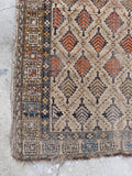 Corner view of distressed vintage rug close-up of intricate hand-knotted weave, serrated leaf design, and worn pile.