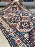 Antique tribal Kazak rug with ram’s horn symbols and protective S hook motifs.
