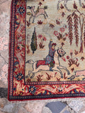 Vintage Persian hunting scene rug showing horsemen, galloping deer, and blooming floral trees.