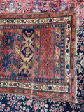 Antique Persian Bidjar rug close-up showing its geometric design and worn wool texture.