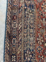Rustic Shiraz rug with alternating color border bands and geometric patterns.
