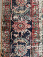 Detailed view of the Herati design on the midnight blue border of the antique rug.