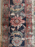 Detailed view of the Herati design on the midnight blue border of the antique rug.