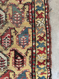 Hand knotted antique Caucasian rug featuring vegetable dyed wool, floppy handle, tribal boteh pattern and yellow field.